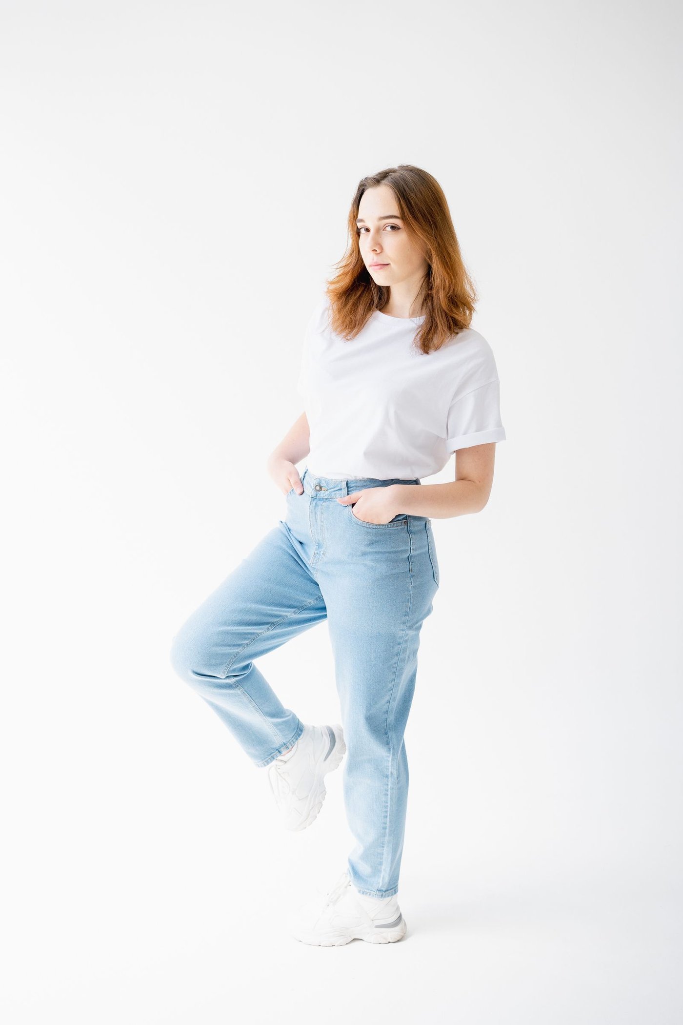 Home Woman in slim blue jeans on a white studio background