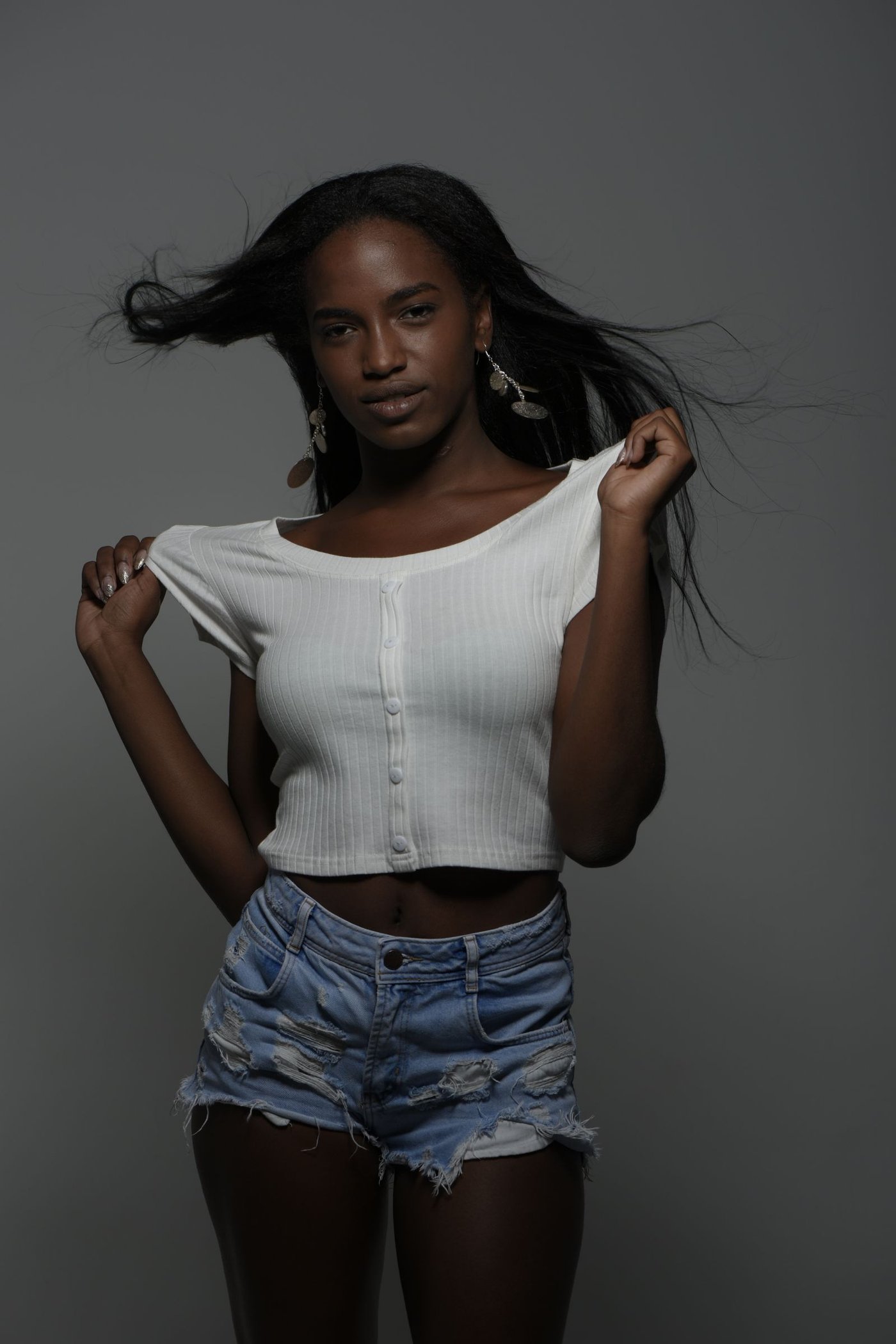 About Woman in dark denim shorts against a dark backdrop