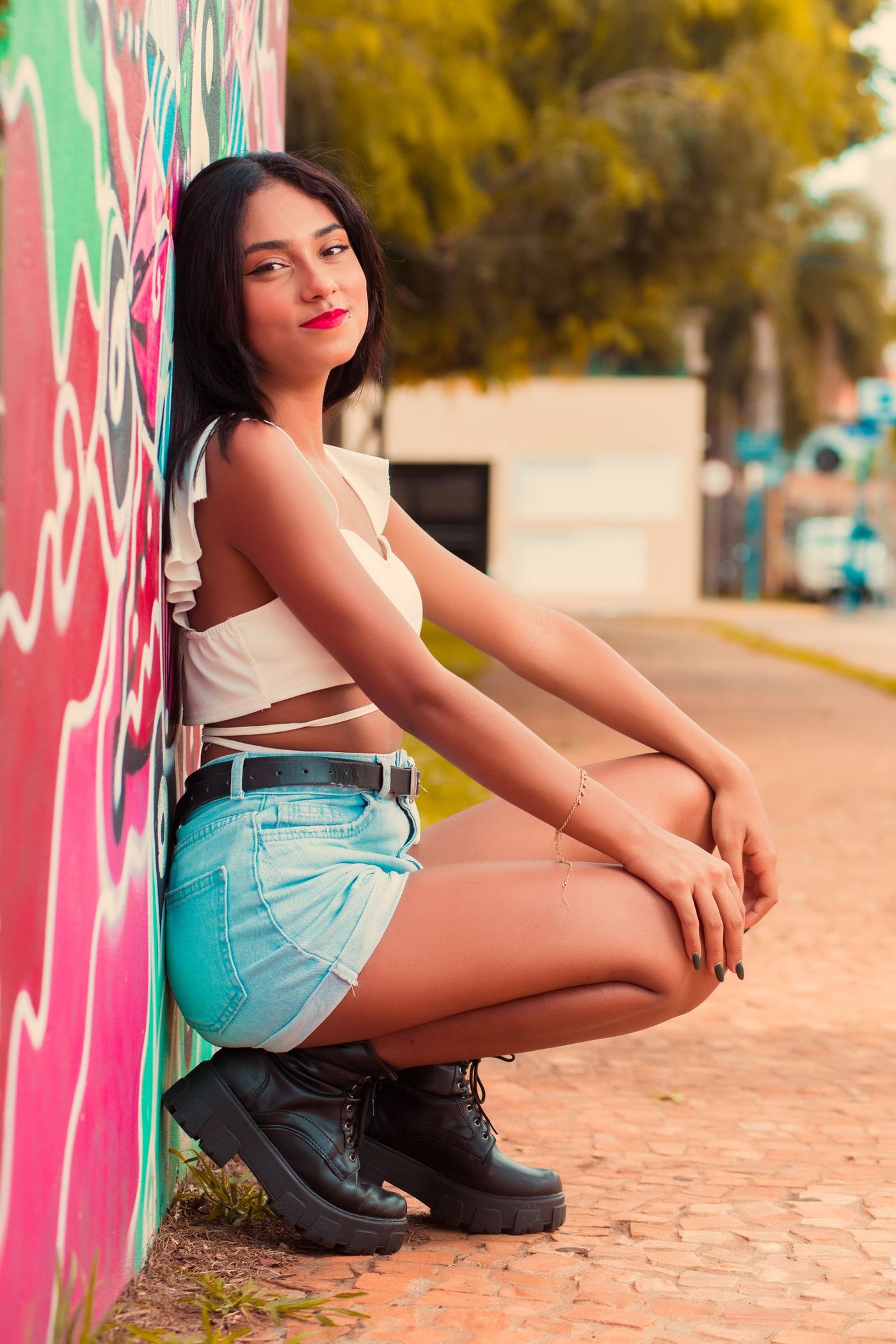 Contact Woman in denim shorts beside a painted wall