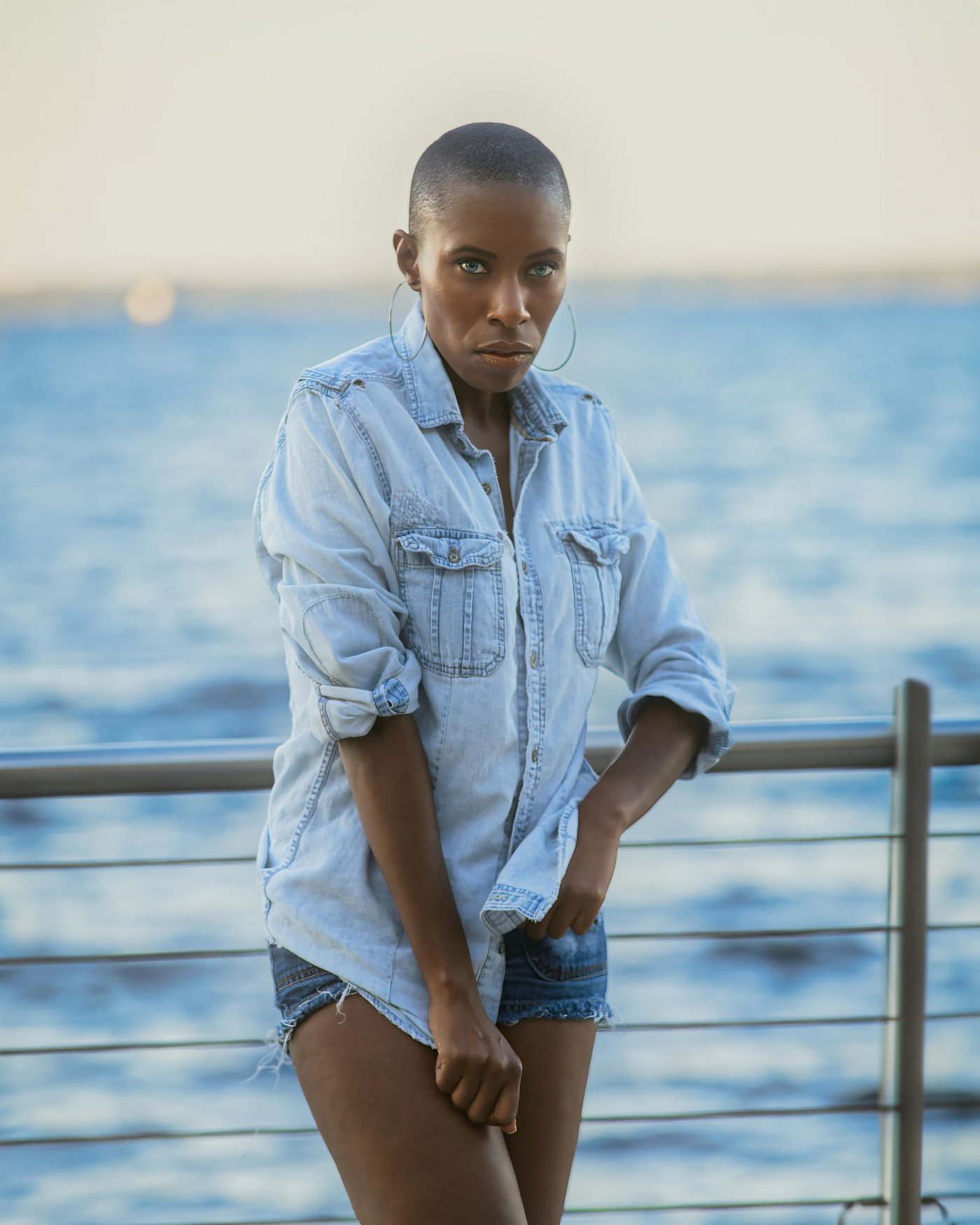 Woman in a blue denim shirt against a plain wall