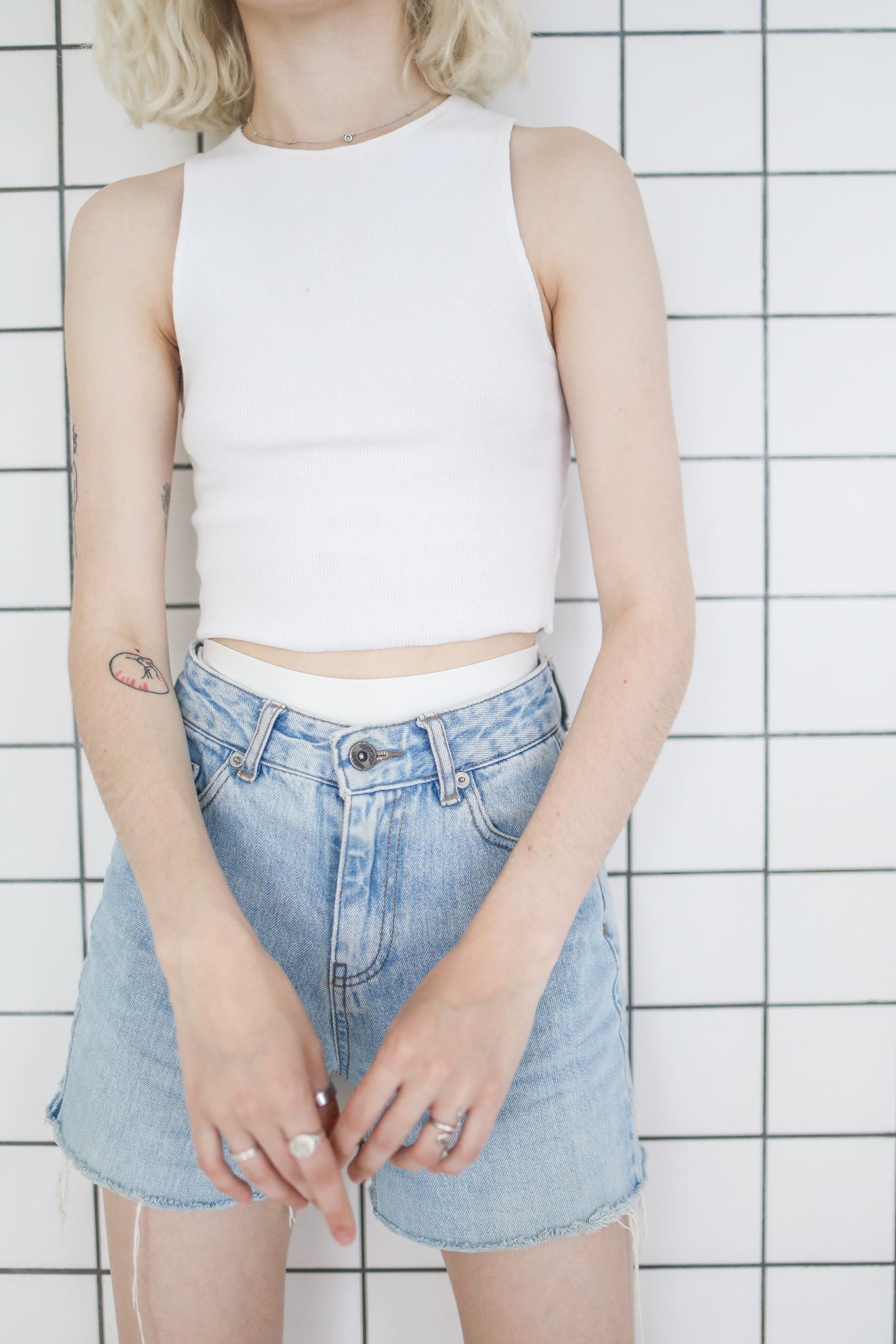 Home Woman standing on a tiled floor in denim shorts